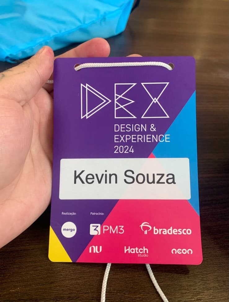 Crachá do Design & Experience 2024 com o nome Kevin Souza, na mão do Kevin