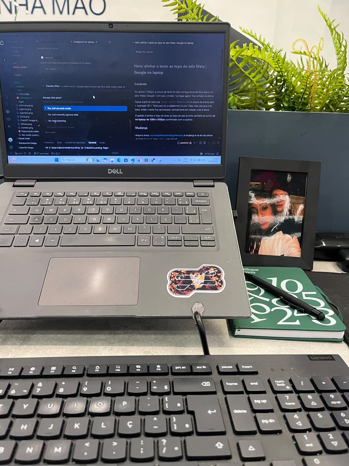 Estação de trabalho: notebook com código aberto, teclado, caderno e porta-retratos