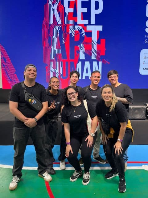 Kevin e equipe no Pixel Show, em frente ao painel “Keep Art Human”